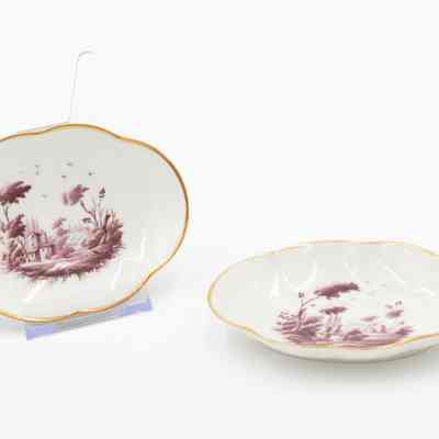 Ashtrays: The image shows two white ceramic ashtrays with burgundy pastoral scenes and gold rims.