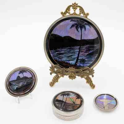 Oasis scene plates and coasters: The image shows decorative plates and coasters with oasis scenes, colored using butterfly wings, featuring palms and water.