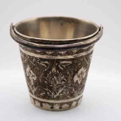 Small silver bucket engraved with leaves.: Up close image of the small silver bucket with a handle engraved with leaves