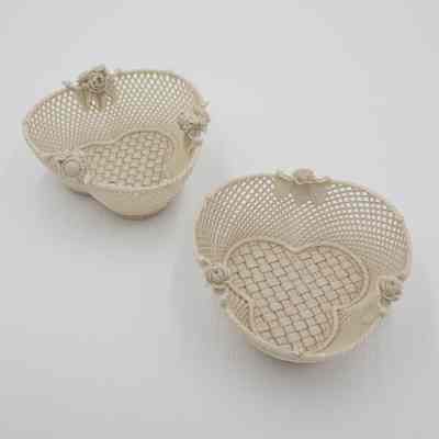 Pair of Belleek baskets: The image features two cream-colored Belleek baskets, porcelain made to seem intricately woven, with delicate flower bunches adorning their rims.