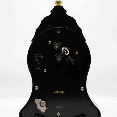 Back of the Jaeger Clock: The back of the clock clearly defines the brand as Jaeger and states it is Swiss. The back is fully black, with silver colored components used to wind the clock. The words labeling each winding part is written in gold.