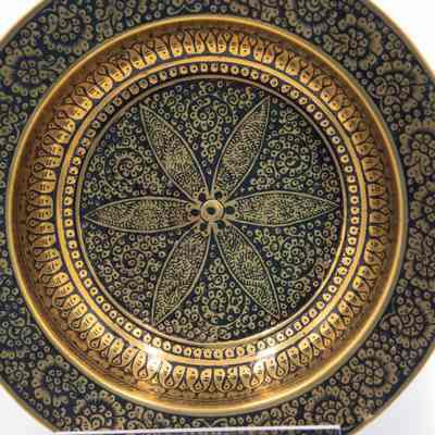 Brass ashtrays with designs: The image shows a brass ashtray adorned with intricate black floral motifs, featuring a detailed central design on a shiny golden surface.