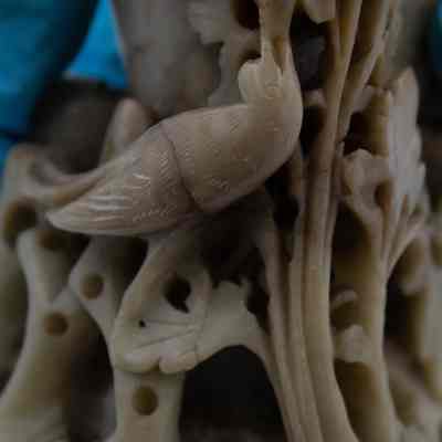 Carved details on the soapstone vase from China.: Up close image of the bird and flowers carved from soapstone on the beige vase.
