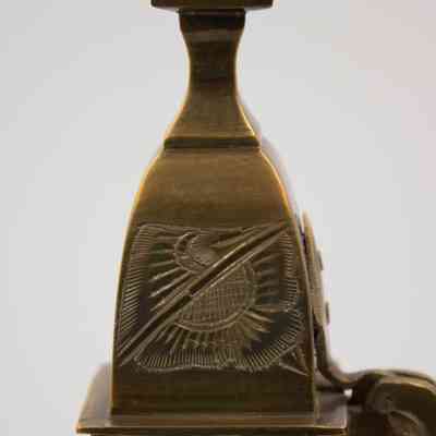 Lid of coffee pot: The image depicts the lid of a large brass coffee pot featuring an intricately engraved floral design with a sun-like pattern.