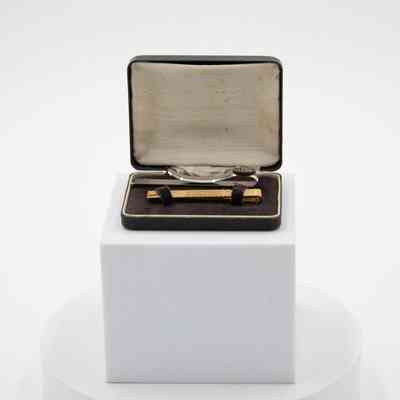 Box with two tie bars: A black box with an open lid displays two gold tie bars inside.
