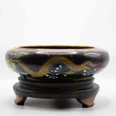 Black enamel bowl with gold dragon on wood stand: The outside of the bowl features the body of the same, second golden yellow dragon. The wooden stand is dark, with 3 feet elevating it.
