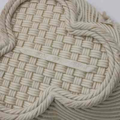 Bottom of Belleek basket: The image shows the intricate woven pattern on the bottom of a porcelain Belleek basket with twisted rope detailing. There is a central flattened stripe with words.