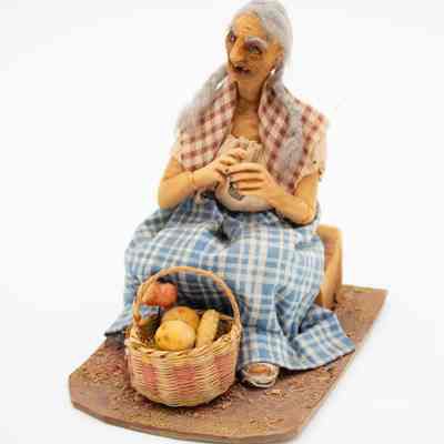Female fruit vendor: A female Andean fruit vendor figurine sits with a woven basket filled with vibrant fruits.