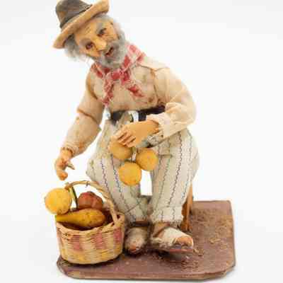 Male fruit vendor: The figurine depicts a male fruit vendor from the Andes in Venezuela, seated with a basket full of colorful fruits.