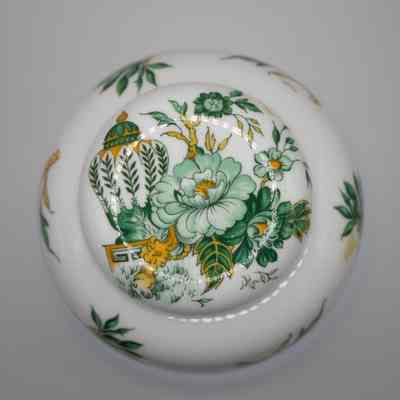 Lid of ginger jar: The image shows a white ginger jar, featuring green and gold flowers in the Kowloon pattern. The lid has the same central painted green flower and tall jar featured on the front of the jar.