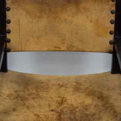 Seat and back of chair: The wooden chair features a leather seat and back, adorned with decorative studs.