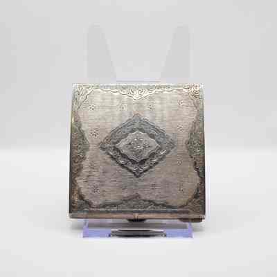 Back of the square silver powder compact.: Image of the back of the square silver compact engraved with swirled floral designs.