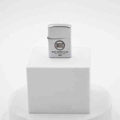 Mene Grande Oil Company Zippo: The steel lighter body has a circle with MGO inside, the Mene Grande Oil Company logo. Underneath it says "MENE GRANDE OIL CO. 1953." There is some wear on the metal near the hinge between the cap and body.