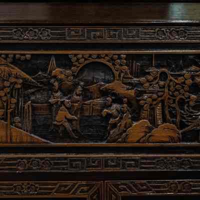 Panel of wooden bar: The carved wooden bar panel depicts intricate scenes with figures, foliage, and structures, showcasing traditional artistry.