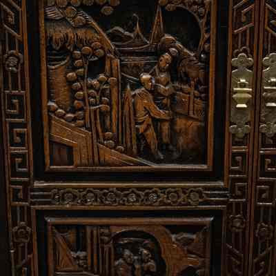 Panel of wooden bar: The image shows an intricately carved wooden bar with decorative motifs and brass hardware.