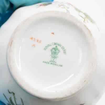 Makers mark on the bottom of the small bowl from Royal Crown Derby porcelain.: Image of the green maker's mark stamp on the bottom of the small white bowl. The stamp indicates the maker, "ROYAL CROWN DERBY," and location of production, "MADE IN ENGLAND." There is also a small crown in the middle of the mark.