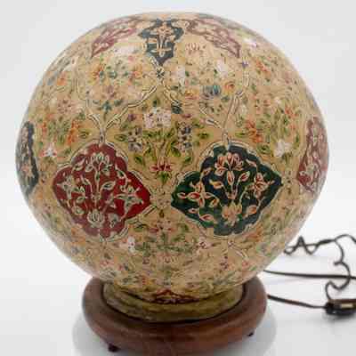Camel bladder lamp: The camel bladder lamp features intricate, brightly colored floral patterns. sitting on a sturdy wooden base.