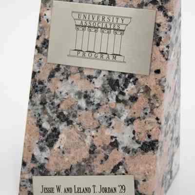 Pink granite polished bookends given to the Jordans by the University Associates Program at Texas A&M University.: Image of the right bookend with two silver plaques. The top plaque reads "UNIVERSITY ASSOCIATED PROGRAM" on a column row, and the bottom reads "JESSIE W. AND LELAND T. JORDAN '29."