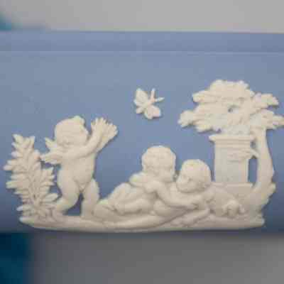 Wedgwood Jasperware square dish: The blue Wedgwood Jasperware square dish features detailed white relief scenes of angels, including one reaching upward, with trees and a decorative column in the background.