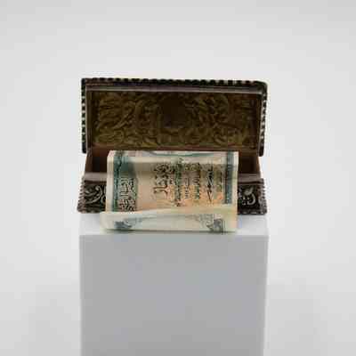 Small pressed silver-plated rectangular box with a 1/4 dinar banknote.: Image of the small silver rectangular box embossed with a leaf swirl design. Cascading out of the box is a green 1/4 dinar banknote. The back of the note has Arabic script.