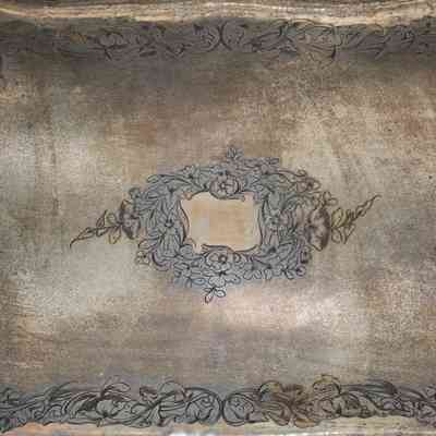 Silver tray: The large rectangular silver tray features intricate molded handles and edges, with a delicate floral pattern adorning its surface.