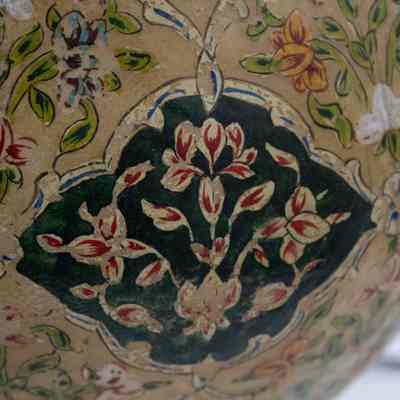 Camel bladder lamp: The camel bladder lamp showcases intricate floral designs in vivid colors, featuring red, green, and yellow, set against a beige background.