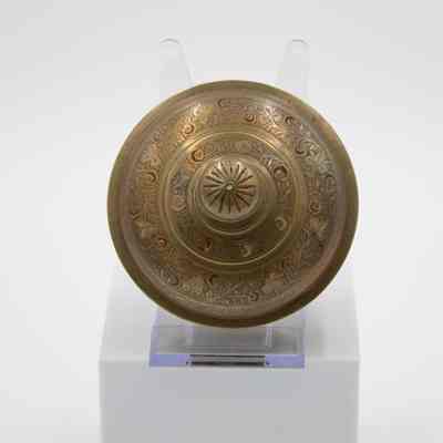Bowl lid: The image features a small brass lid intricately engraved with a red floral motif.