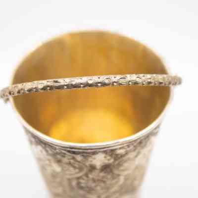 Silver bucket: The image shows an ornate silver bucket with a floral design and textured handle.