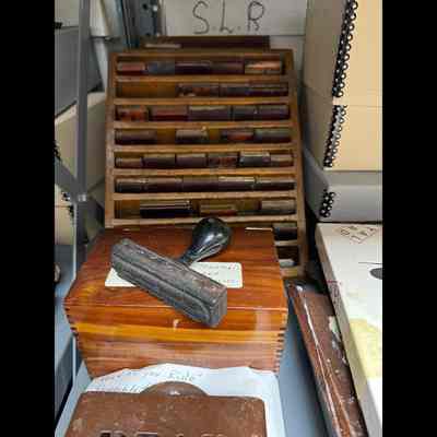 Rubber stamps for office use contained in angled wooden rack.