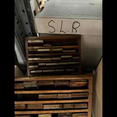 Rubber stamps for office use contained in angled wooden rack.