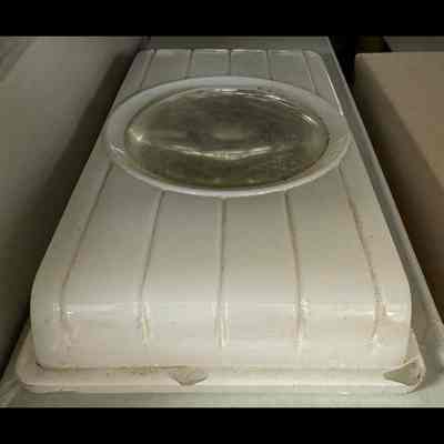 Glass object (lamp shade). Round lens in middle (transparent), with white glass surround. Rectangular.