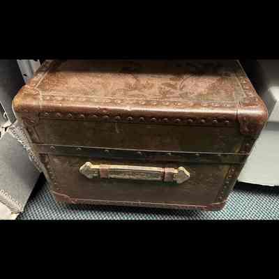 Suitcase. Leather-covered, brown in color. Metal-reinforced corners and edges.