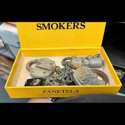 Yellow Panetela cigar box containing several Adlake padlocks and a short section of linked chain.