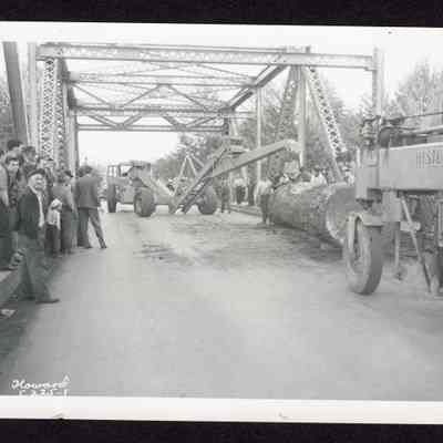 Photograph of workers moving a log off a bridge, circa 1950