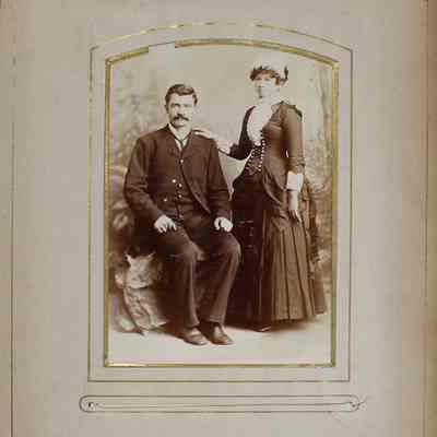 2016-024-012_img-004: Page 2 of photograph album 2016.024.012: Unknown couple; man is sitting on a rock in a suit, woman is standing in a long sleeve dress and a white hat. Studio Brisbois Leadville Colorado.
