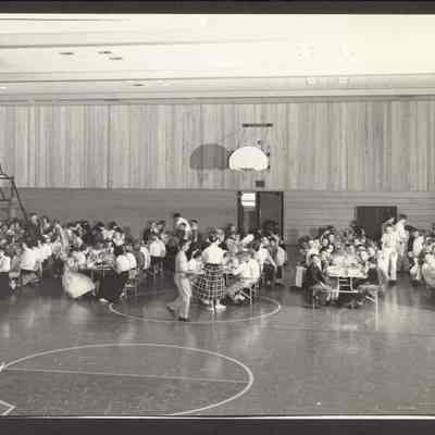 Photograph of school lunch in the gym. Date unknown.
