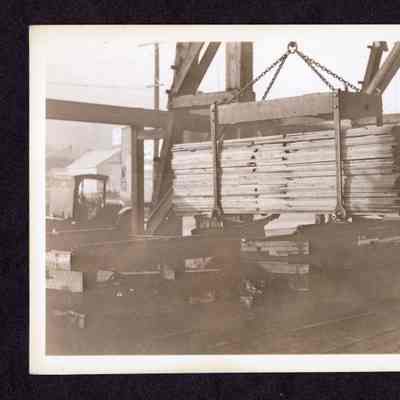 Photograph on postcard of traveling crane cage setting load of lumber on rolls at Jones Lumber Company, Portland, Oregon, date unknown