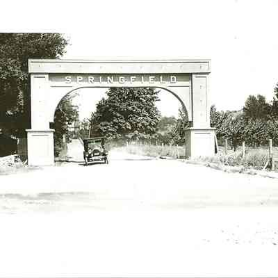 Photograph of a car going through the Springfield Arch from the Pacific Highway, Springfield, Oregon