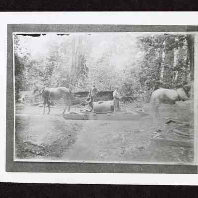 Photograph of two unknown men with tanks and skids for watering