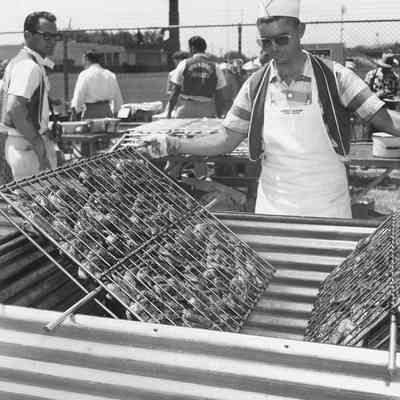 Photograph of unknown man turning broiler rack of chicken, 1957