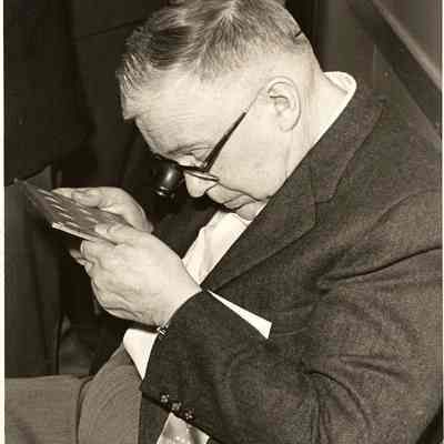 Photograph of Claude Washburne closely examining unknown object