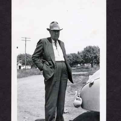 Photograph of unknown man standing in front of a car