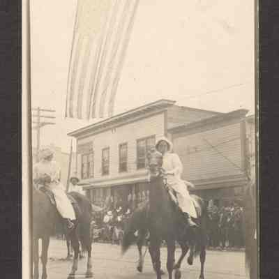 Photograph of a Post Card of a parade with three women on horseback. Date unknown.