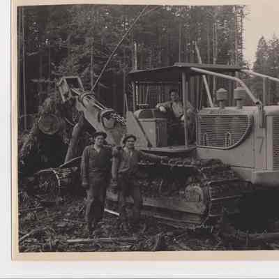 Photograph of three men by a caterpillar