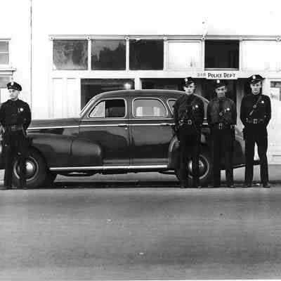 Photograph of uniformed officers posed in front of car at police department, Springfield, Oregon, date unknown