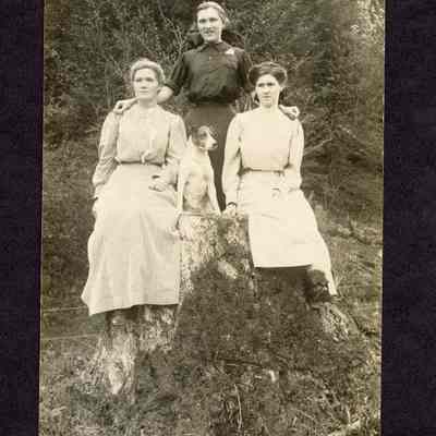 Photograph on postcard of three women and a dog