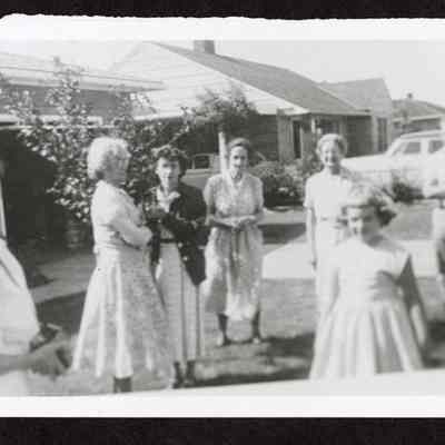 Photograph of seven people outside a house