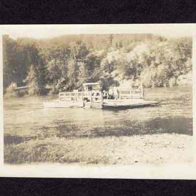 Photograph of car and unknown person on a small river ferry