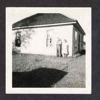 Photograph of a man and woman in front of a house, circa 1910