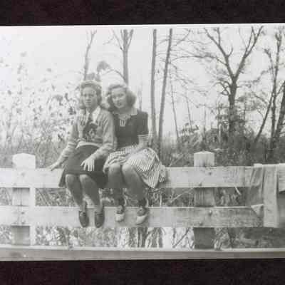 photograph of Millrace with two women sitting on fence, date unknown